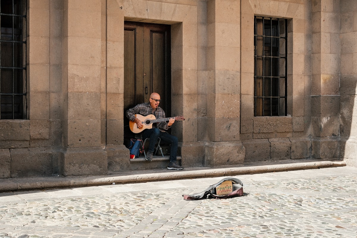 Man playing Spanish guitar in front of a building with romantic atmosphere | Audaz Revista