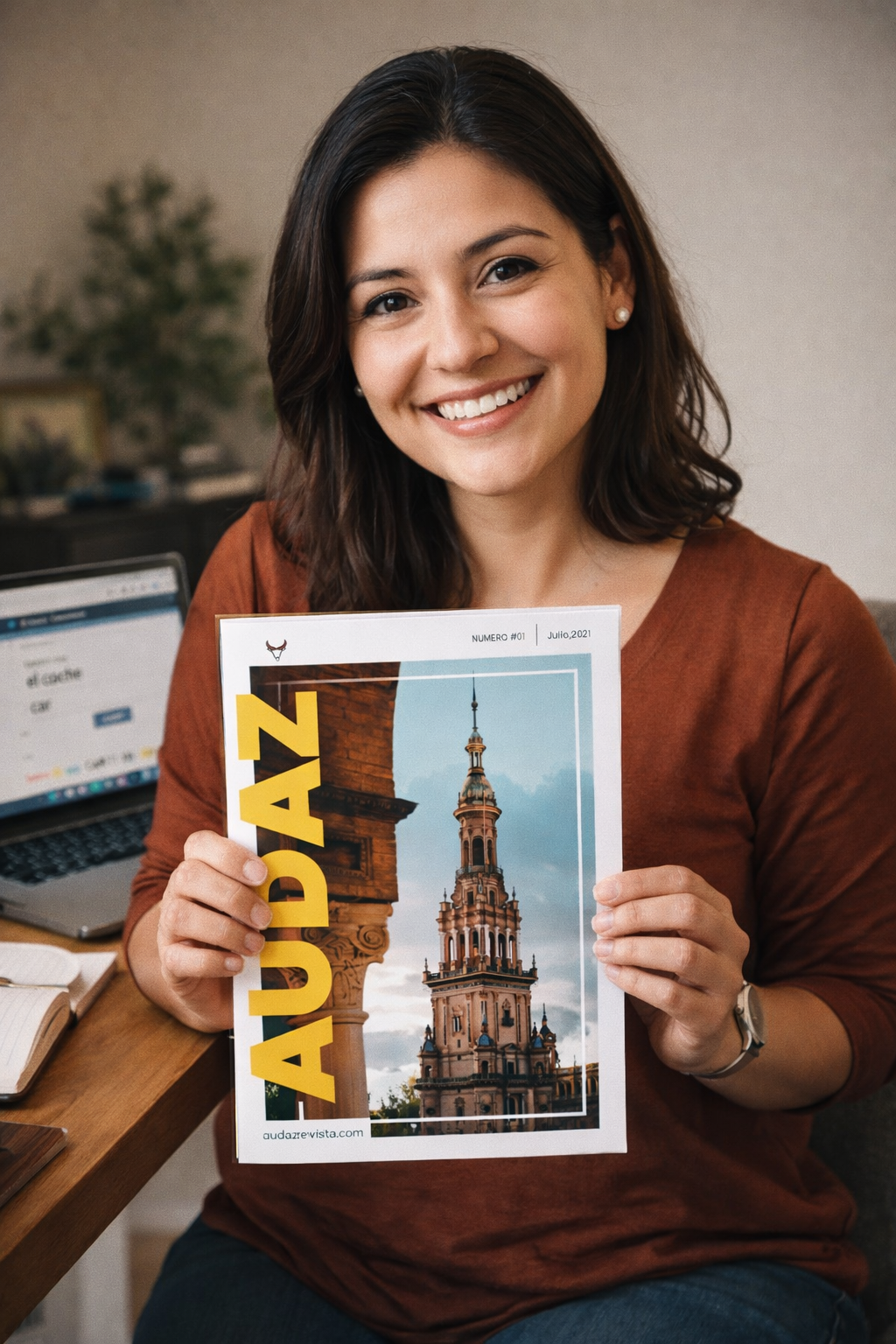 Woman smiling while holding Audaz Revista Spanish learning magazine with laptop and study notes in background | Audaz Revista