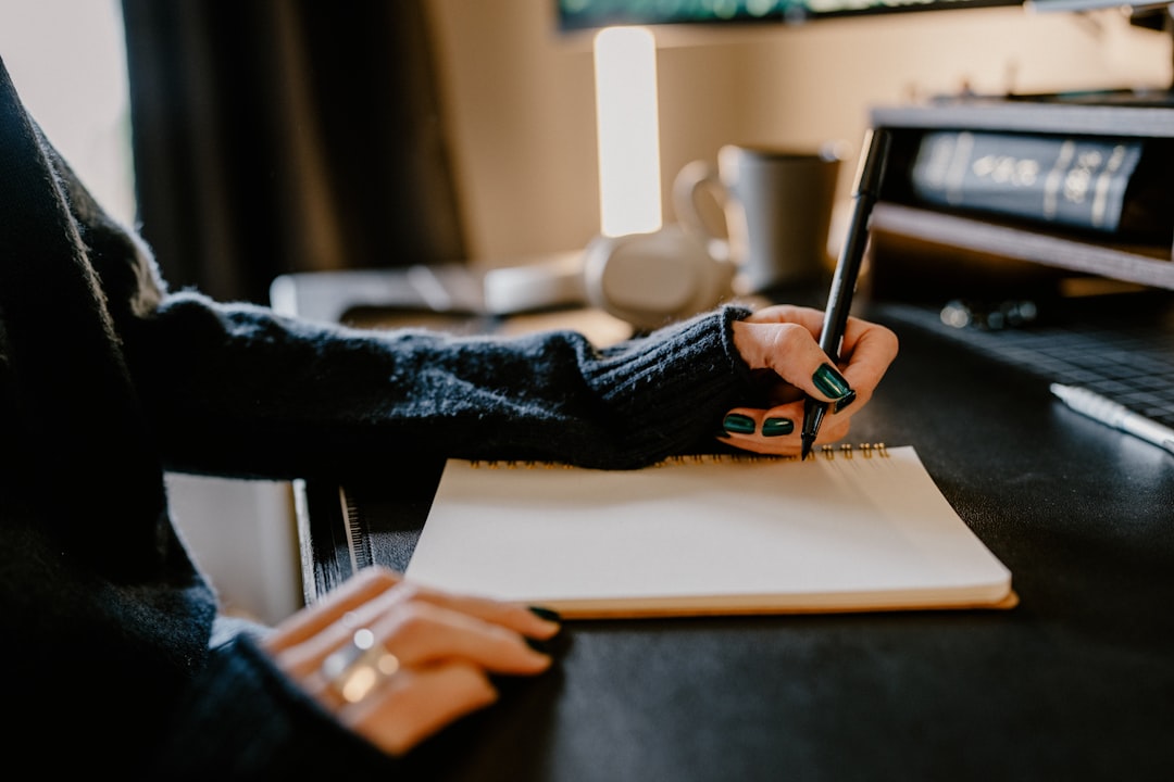 A learner writing Spanish words from memory in a notebook
