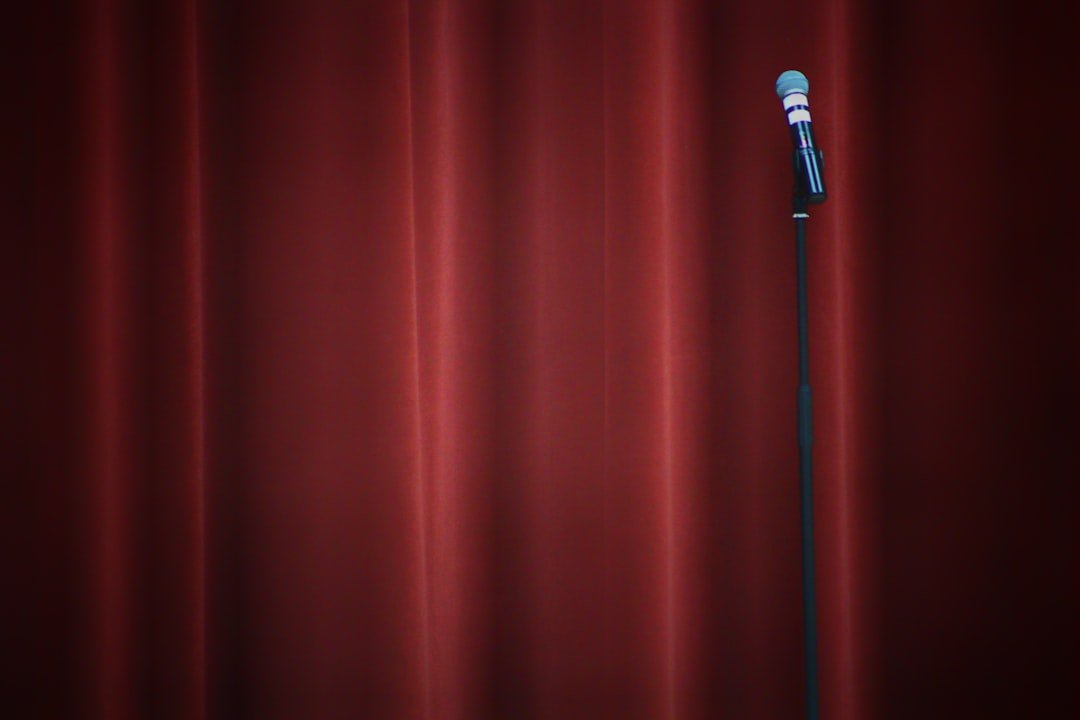 A stand-up comedy microphone on a stand under a spotlight on an empty stage