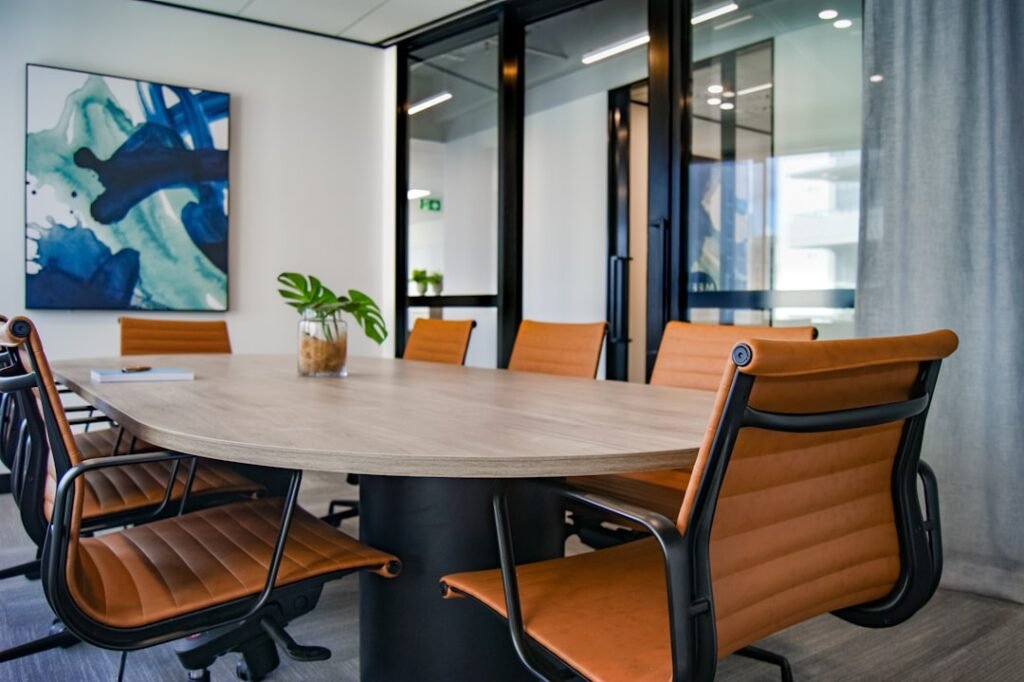 An empty meeting room with tan leather chairs around a wooden table, set for a job interview