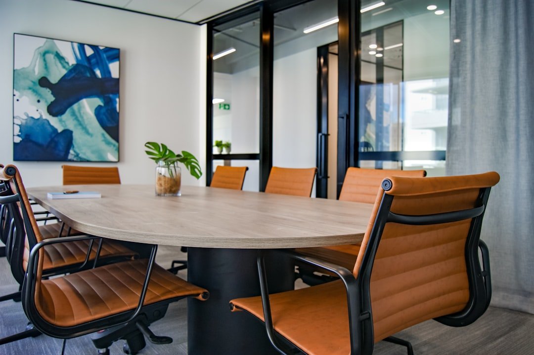 An empty meeting room with tan leather chairs around a wooden table, set for a job interview
