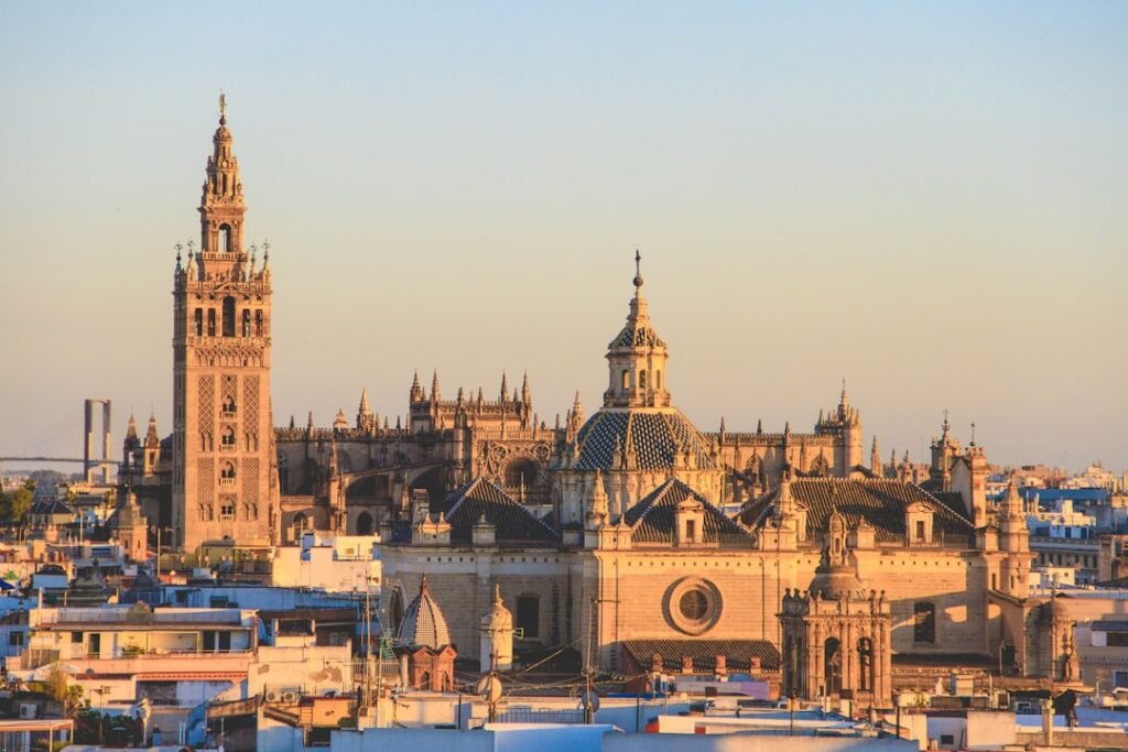 Rooftop view over Seville at golden hour, with the cathedral and Giralda tower above the old town