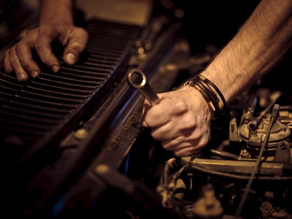 A mechanic working under the bonnet of a car in a garage