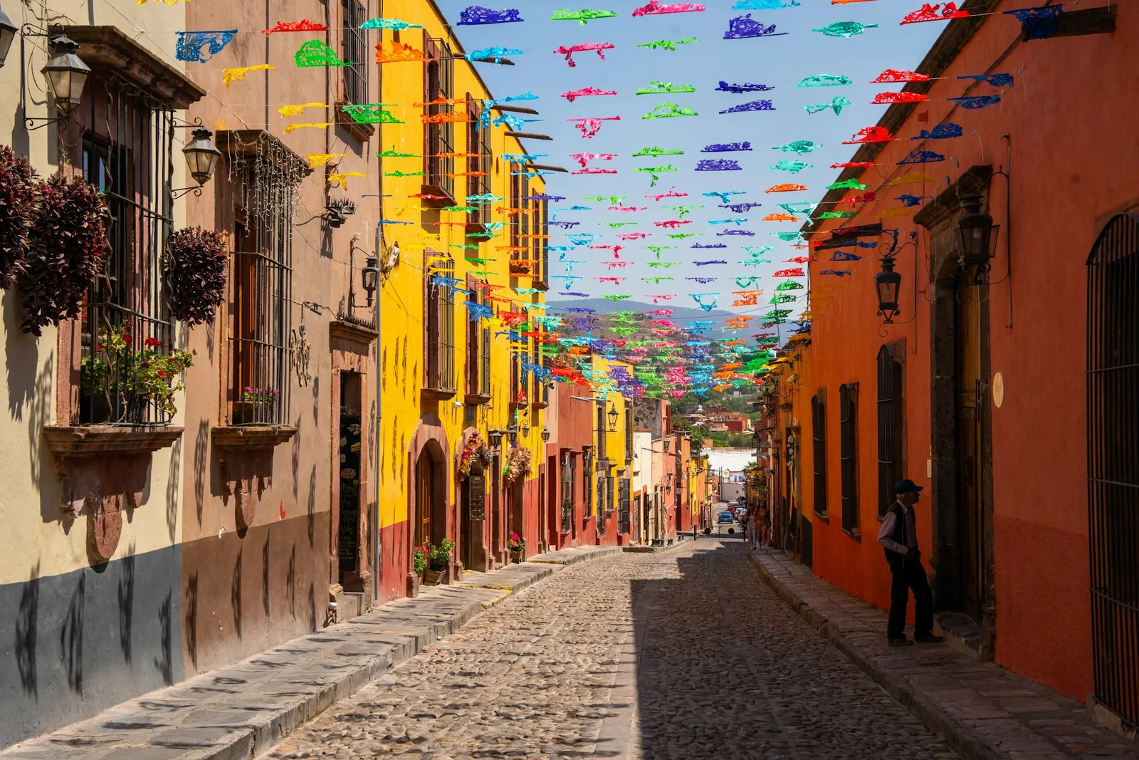 A cobblestone street lined with colourful papel picado flags